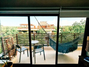 A balcony with a hammock, two chairs, and a table. - Luxury 2BR Penthouse in the Jungle. Nature, Pools & Cenotes in Tulum (Tulum)