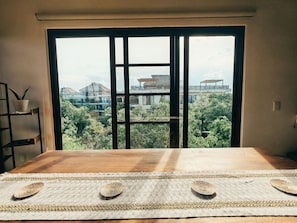 A room with a large window, a wooden table, and a woven mat. - Luxury 2BR Penthouse in the Jungle. Nature, Pools & Cenotes in Tulum (Tulum)