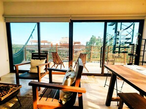 A room with a large window, a wooden table, and a hammock. - Luxury 2BR Penthouse in the Jungle. Nature, Pools & Cenotes in Tulum (Tulum)