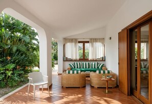 A room with a green-striped sofa, wicker chairs, a small table, and a white chair. - Babette's House (Puglia)
