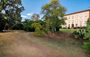 A building with a symmetrical facade, a well-maintained lawn, and a variety of trees and shrubs. - Luxurious home in Montaut with private swimming pool, can be inside or outside (Montaut)
