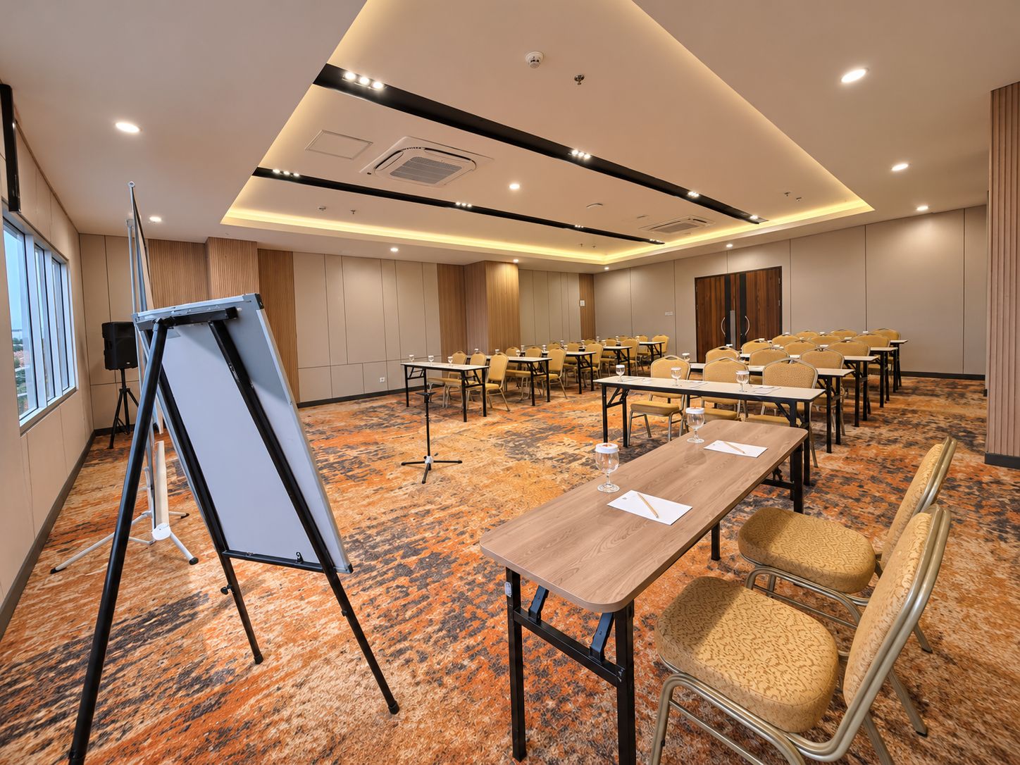 Un salón de conferencias con mesas, sillas, una pizarra y suelo alfombrado.