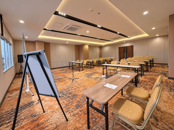 A conference room with tables, chairs, a whiteboard, and a carpeted floor.