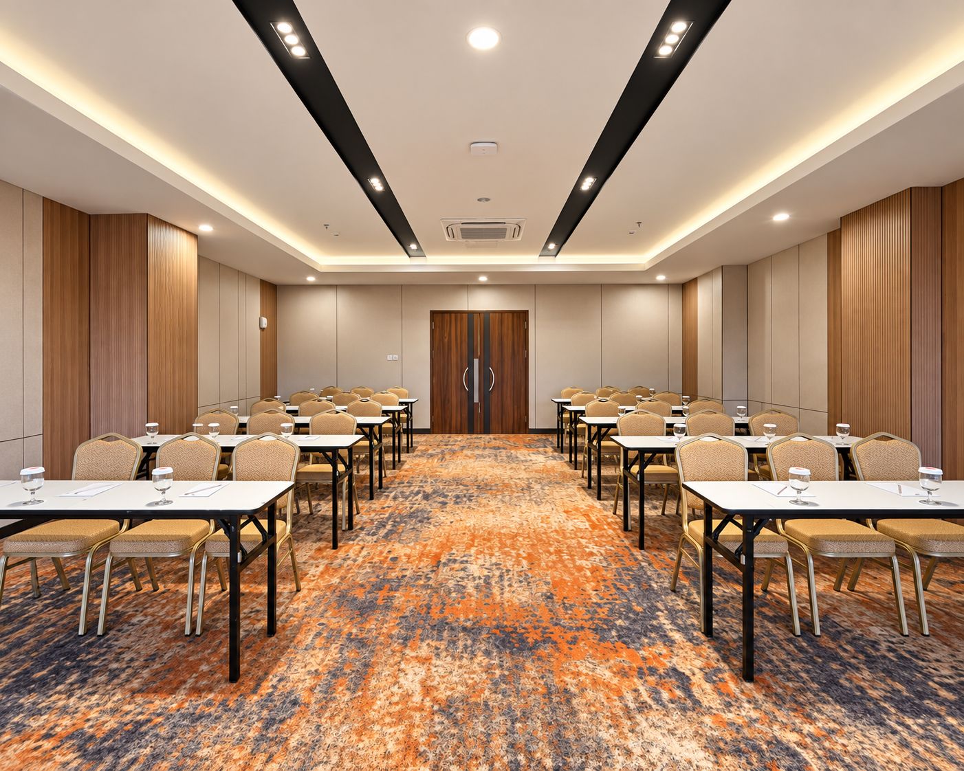 Una sala conferenze con tavoli e sedie, un tappeto decorato e una porta in legno.