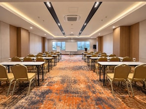 Uma sala de conferência com mesas, cadeiras, piso coberto por carpete e uma tela de projetor.
