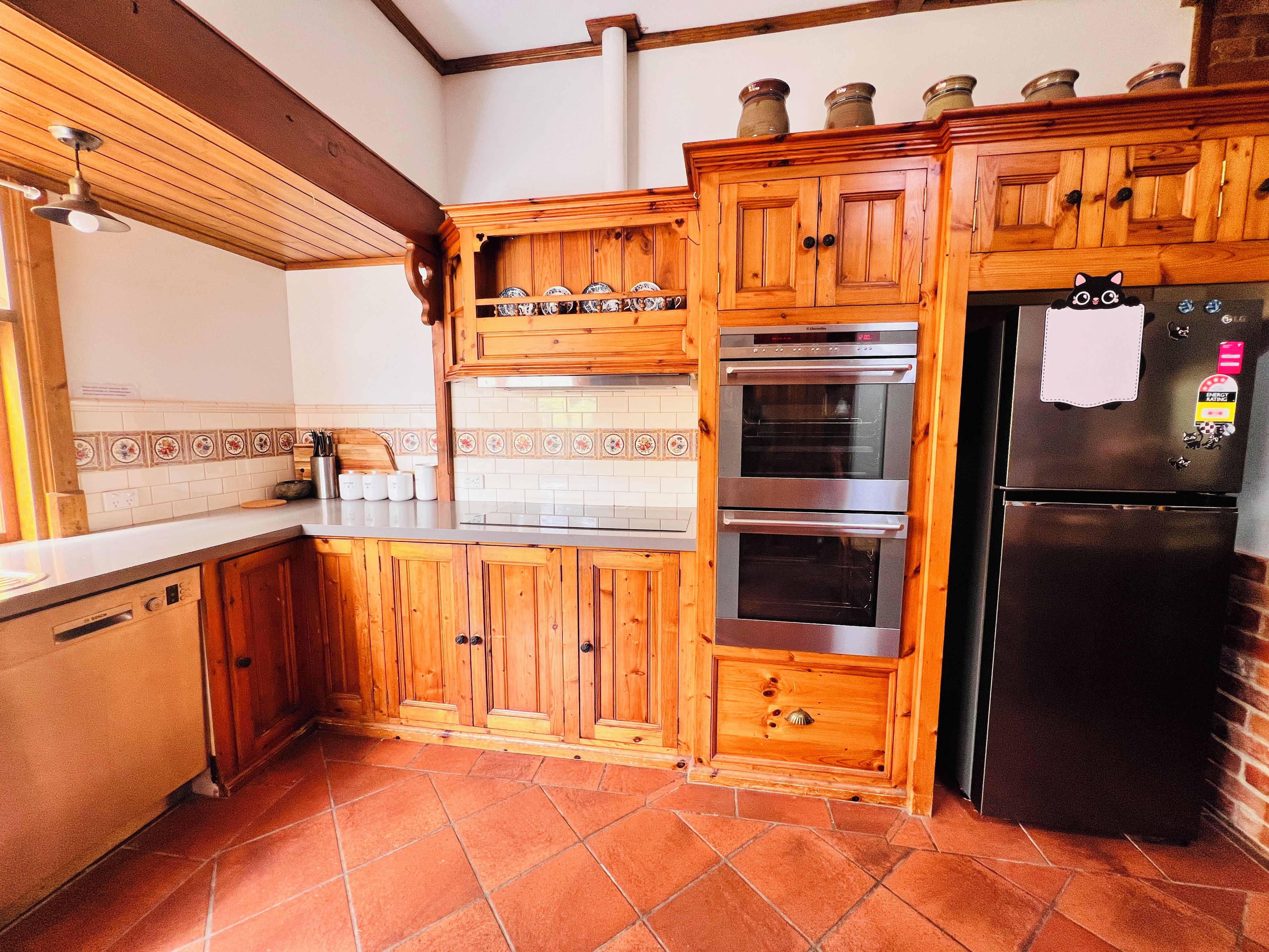 Een keuken met houten kastjes, een oven van roestvrij staal en een zwarte koelkast.