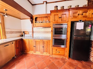 A kitchen with wooden cabinets, a stainless steel oven, and a black refrigerator.