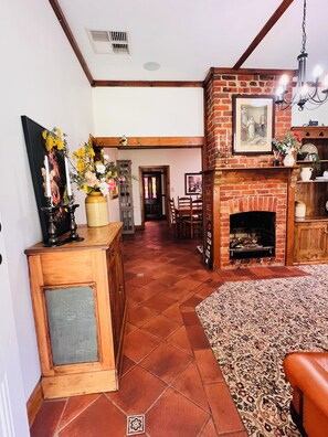 Uma sala de estar ampla com lareira, uma mesa de jantar e um tapete grande.