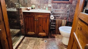 Une salle de bain avec un meuble-lavabo en bois, une cabine de douche en verre et une fenêtre.