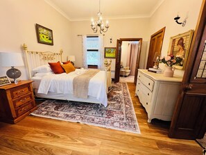 Quarto com cama, mesas de cabeceira, cômoda, lustre e tapete.