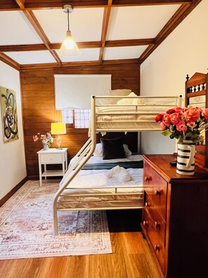 A bunk bed room with a wooden ceiling, a bedside table with a lamp, a dresser, and a rug. - 5-bedroom vineyard cottage for groups McLaren Vale (Blewitt Springs)
