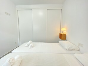 A hotel room with a bed, a nightstand with a lamp, and a set of white towels. - Apartment in Nerja With Sea Views & Pool (Nerja)