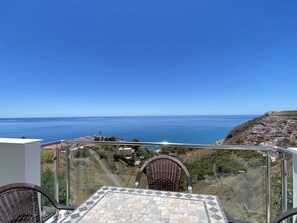 A balcony with a view of the sea and a hillside town. - Apartment in Nerja With Sea Views & Pool (Nerja)