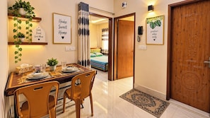 A dining area with a table set for four, a wooden door, and a wall-mounted telephone.
