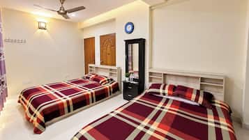A hotel room with two beds, a wardrobe, a mirror, and a ceiling fan.