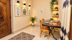 A dining area with a wooden table, four chairs, a potted plant, and framed inspirational quotes on the wall. - AST Guest House (Dhaka)
