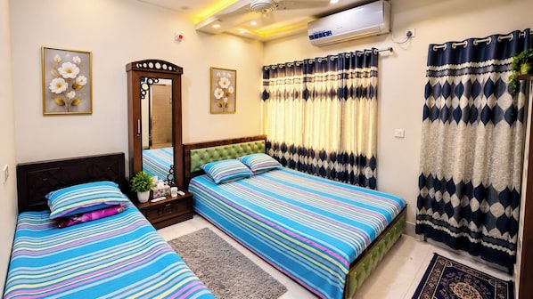 A bedroom with two beds, a mirror, and a window with curtains.
