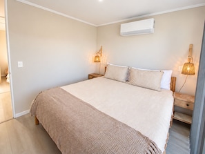 Ein Schlafzimmer mit einem großen Bett, zwei Nachttischen, einer Wandklimaanlage und zwei Wandleuchten.