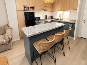 Eine moderne Küche mit Kochinsel, Barhocker und Holzschränken.