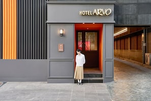 Entrada de un hotel con diseño moderno, un letrero que dice 'HOTEL ARVO' y una placa con el número 66.