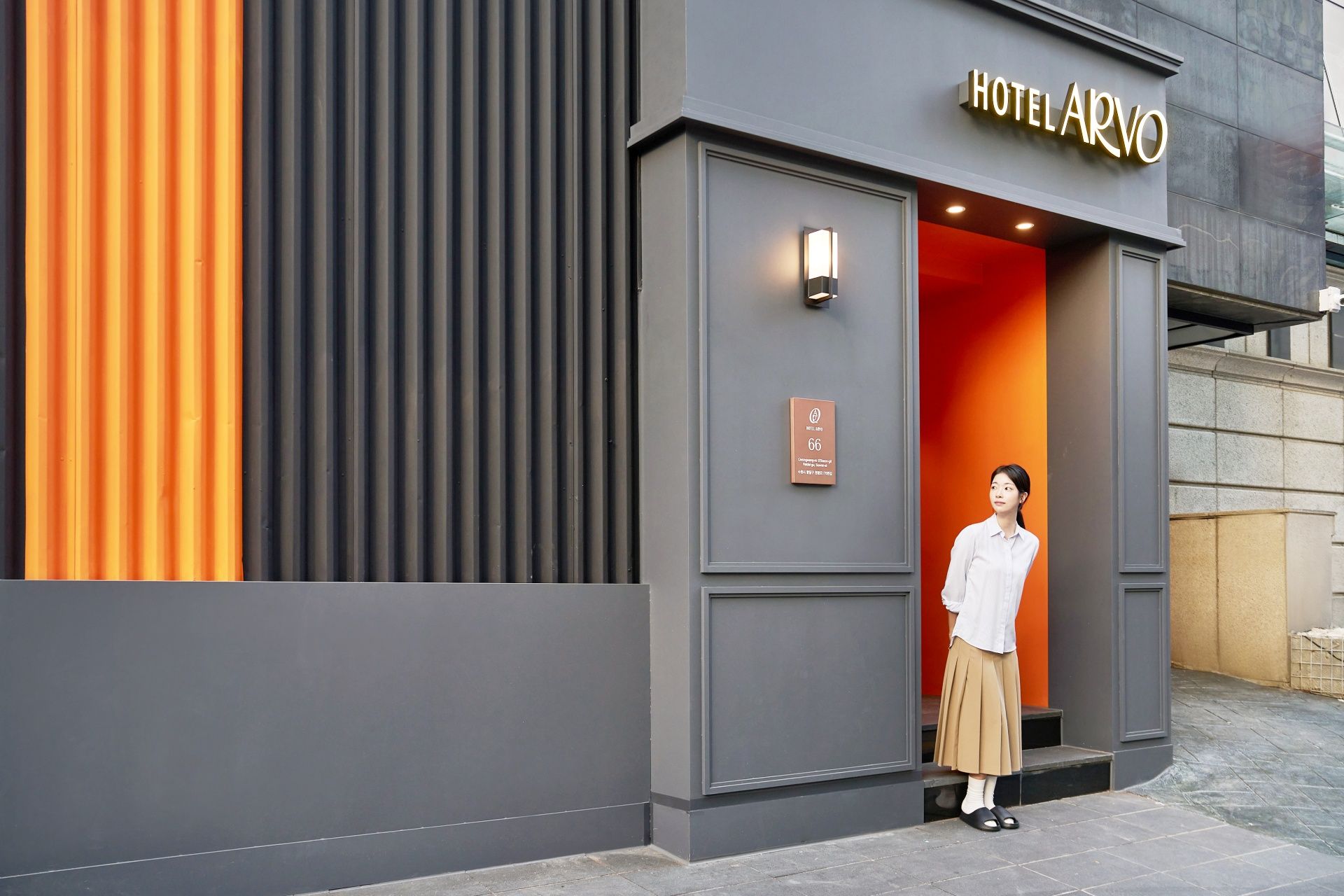 A hotel entrance with a modern design, featuring a bold color contrast between grey and orange.