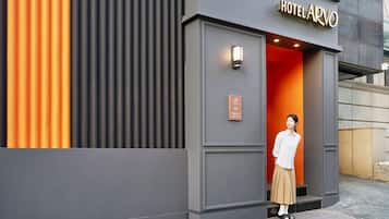 A hotel entrance with a modern design, featuring a bold color contrast between grey and orange.