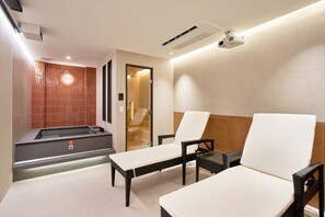 Un moderno spa con hidromasaje, dos sillones de descanso y una pared de madera.
