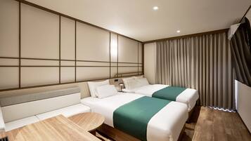 A hotel room with two beds, a sofa, a small table, and a view of the outside.