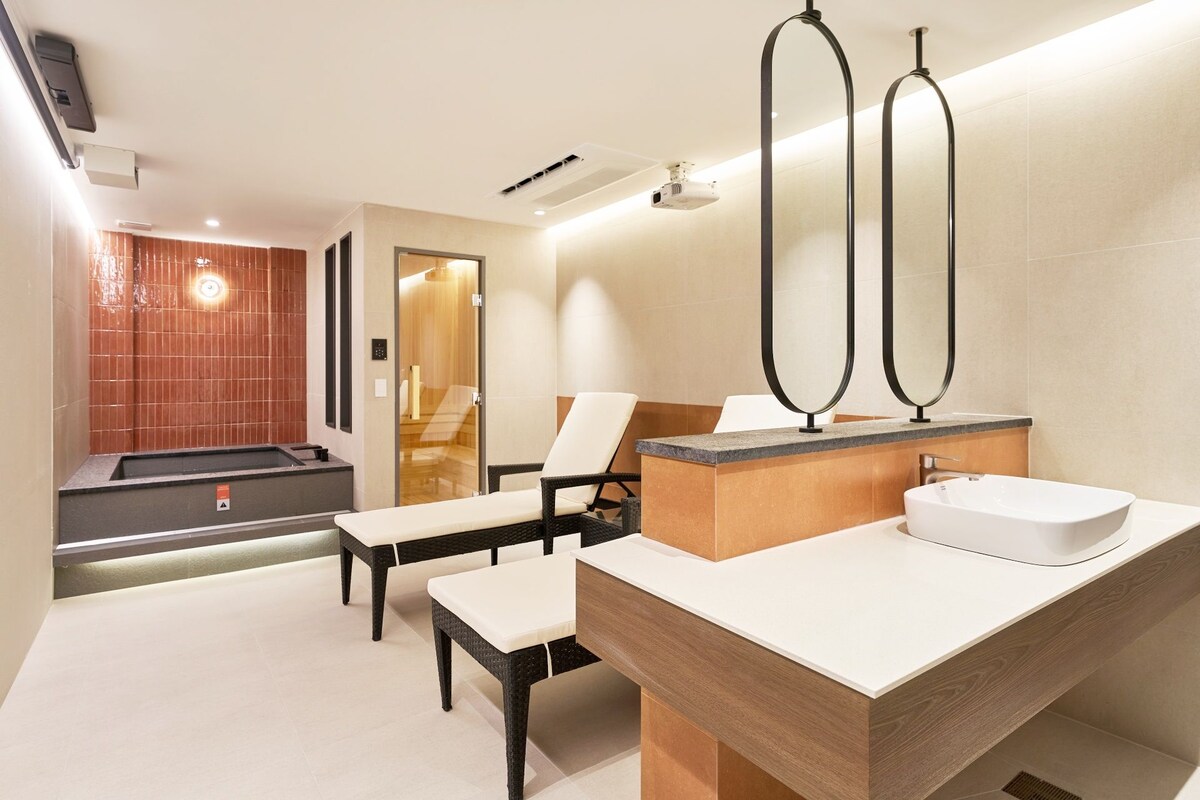 Un baño moderno con jacuzzi, un espejo grande y una zona de estar.