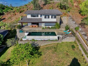 A two-story house with a swimming pool, a patio with outdoor furniture, and a stone staircase leading to the upper level. - Villa Marines (nosy be)