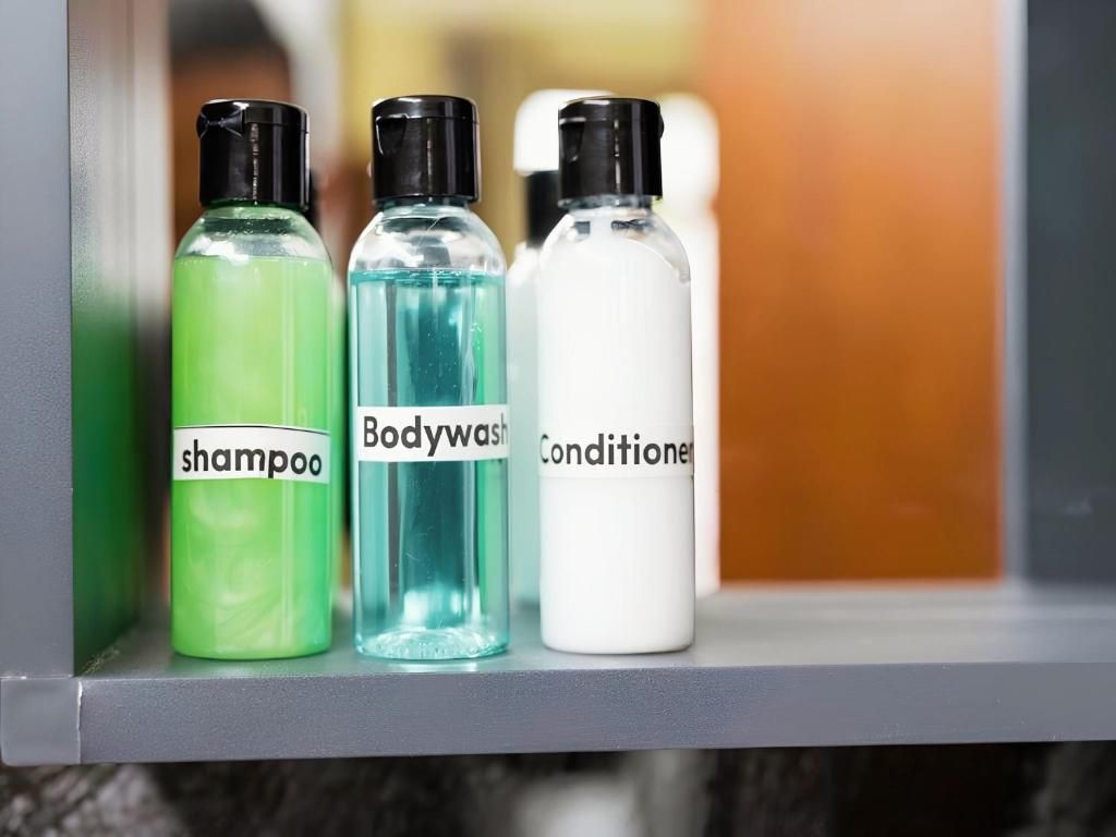 Tres botellas de champú, gel de baño y acondicionador sobre una estantería.