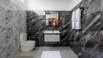 A modern bathroom with a marble wall, a toilet, a sink, and a mirror.