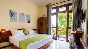 A hotel room with a large bed, a wooden wardrobe, a balcony with a view, and artwork on the wall. - Mashmellow Resort & Spa (Galle)