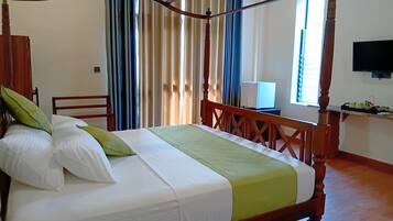 A four-poster bed with a green bedspread, white pillows, and a wooden headboard.