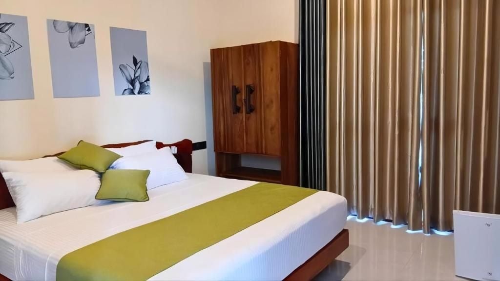 Una habitación de hotel con cama, armario de madera y ventana con cortinas.