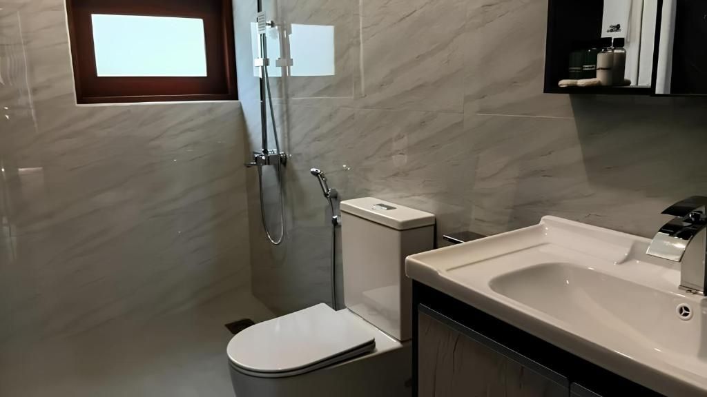 A modern bathroom with a toilet, a sink, and a shower.