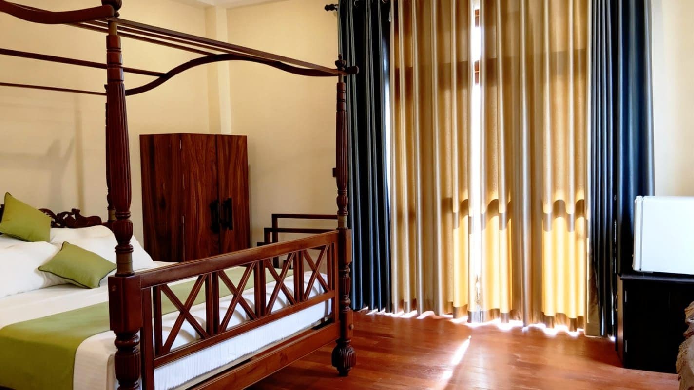 A four-poster bed with a wooden frame, a green pillow, and a white bedspread.