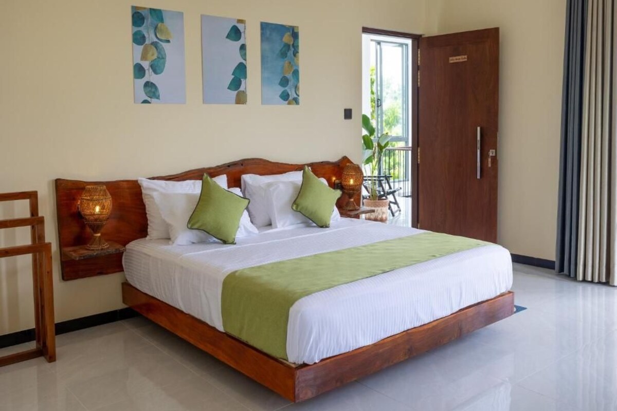 A spacious bedroom with a large bed, a wooden headboard, and a nightstand with a lamp.