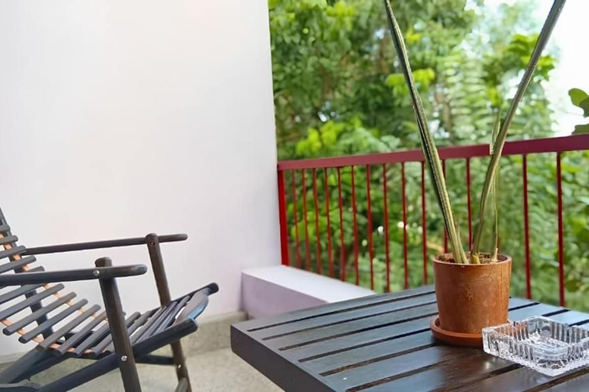 A balcony with a wooden table, a potted plant, and a metal chair.