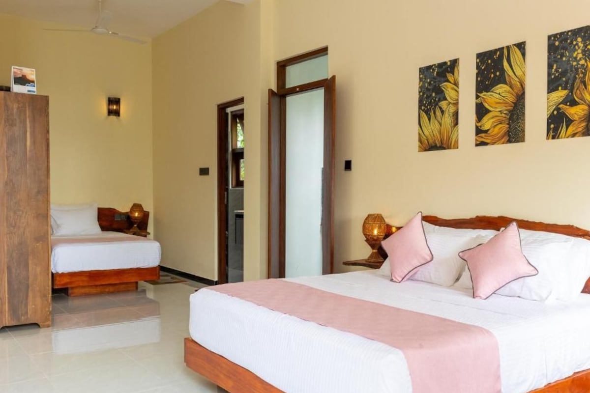 A hotel room with a large bed, a smaller bed, a wardrobe, and a door leading to another room.