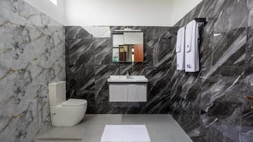 Une salle de bain moderne avec un mur en marbre, des toilettes, un lavabo et un miroir.