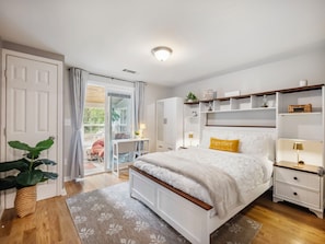 A bedroom with a bed, bedside tables, a wardrobe, a desk, and a chair.