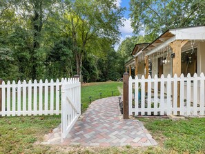 A white picket fence, a brick pathway, and a covered porch with string lights. - Charm and Cozy! (Toccoa)