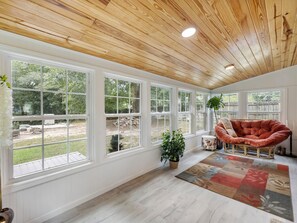 A spacious room with large windows, a wooden ceiling, and a cozy seating area.
