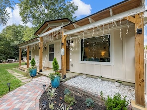 A house with a covered porch, outdoor seating, and decorative lights.