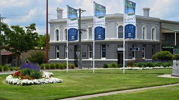 A historic building with flags, a landscaped garden, and a sign for Mansfield High Country Lakes and Rivers.