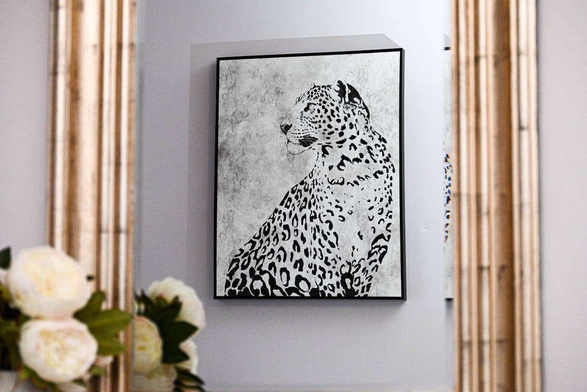 A framed artwork of a leopard on a wall.