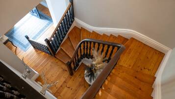 A wooden staircase with a handrail, leading to a landing with a blue carpet.