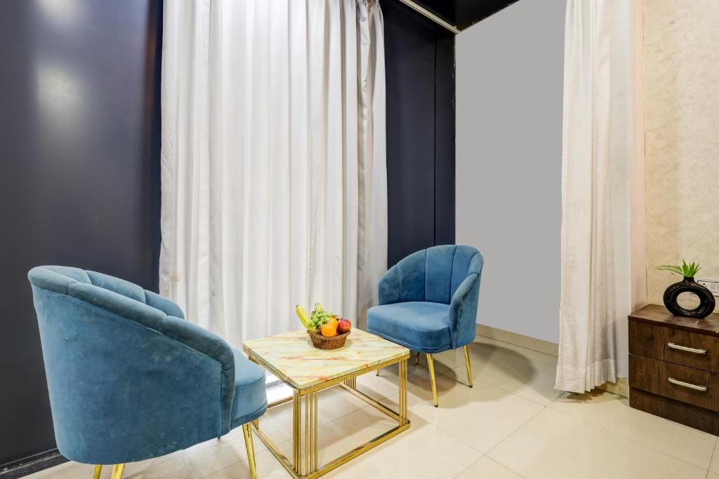 Una habitación con dos sillones azules, una mesita con una cesta de fruta y un mueble con una planta.