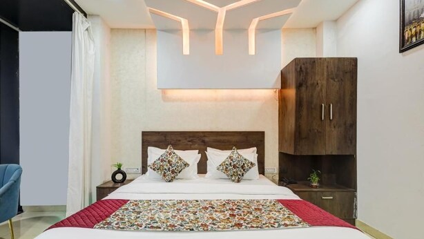 A modern bedroom with a bed, nightstands, a wardrobe, and a unique ceiling design. - Hotel Priyaj  (Jaipur)
